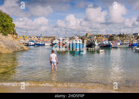 Ein Mann, der im Meer am historisch arbeitenden Newquay Harbour in Newquay in Cornwall steht. Stockfoto