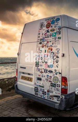 Verschiedene bunte Aufkleber schmücken die Hintertür eines Wohnwagens, der bei Little Fistral in Newquay in Cornwall geparkt ist. Stockfoto