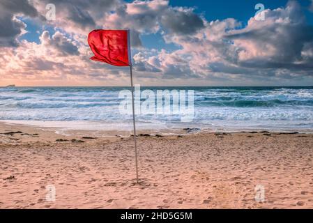 Eine rote RNLI-Flagge für Gefahr, die bei starken Winden am Fistral Beach in Newquay in Cornwall flattert. Stockfoto