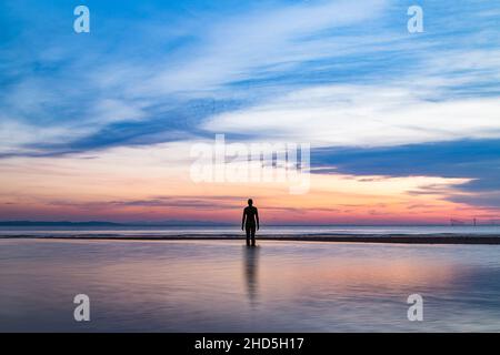 Ein Eiserner Mann, der bei Sonnenuntergang gefangen wird, wenn die Flut eintrifft. Stockfoto