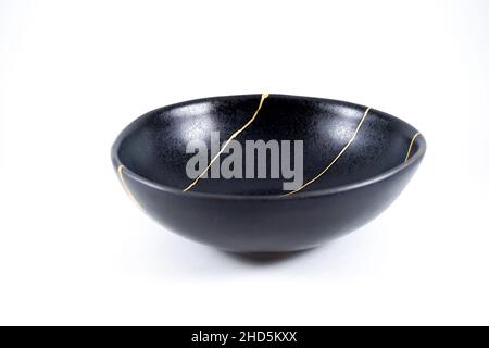 Kintsugi Gold Risse Restaurierung, japanische schwarze Schale mit der antiken Kintsukuroi Restaurierung Technik, die Schönheit der Unvollkommenheiten, fixiert, darstellen Stockfoto