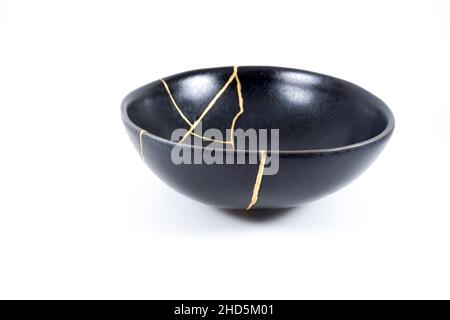 Kintsugi Gold Risse Restaurierung, japanische schwarze Schale mit der antiken Kintsukuroi Restaurierung Technik, die Schönheit der Unvollkommenheiten, fixiert, darstellen Stockfoto