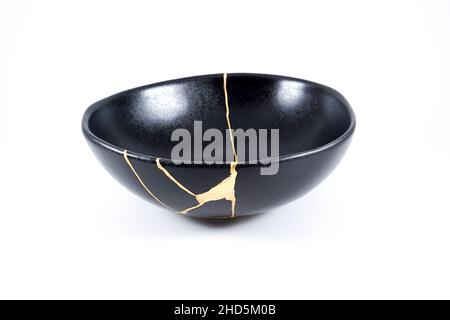 Kintsugi Gold Risse Restaurierung, japanische schwarze Schale mit der antiken Kintsukuroi Restaurierung Technik, die Schönheit der Unvollkommenheiten, fixiert, darstellen Stockfoto