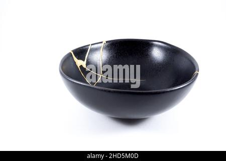 Kintsugi Gold Risse Restaurierung, japanische schwarze Schale mit der antiken Kintsukuroi Restaurierung Technik, die Schönheit der Unvollkommenheiten, fixiert, darstellen Stockfoto