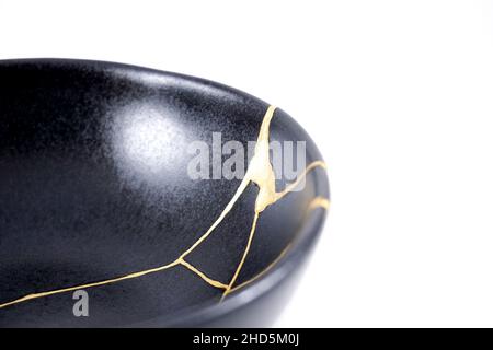 Kintsugi Gold Risse Restaurierung, japanische schwarze Schale mit der antiken Kintsukuroi Restaurierung Technik, die Schönheit der Unvollkommenheiten, fixiert, darstellen Stockfoto