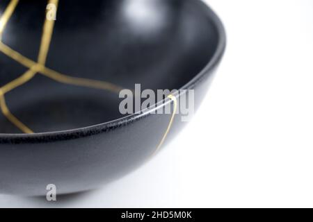 Kintsugi Gold Risse Restaurierung, japanische schwarze Schale mit der antiken Kintsukuroi Restaurierung Technik, die Schönheit der Unvollkommenheiten, fixiert, darstellen Stockfoto