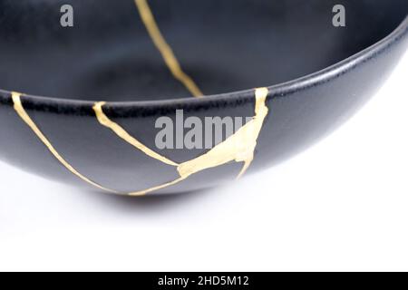 Kintsugi Gold Risse Restaurierung, japanische schwarze Schale mit der antiken Kintsukuroi Restaurierung Technik, die Schönheit der Unvollkommenheiten, fixiert, darstellen Stockfoto