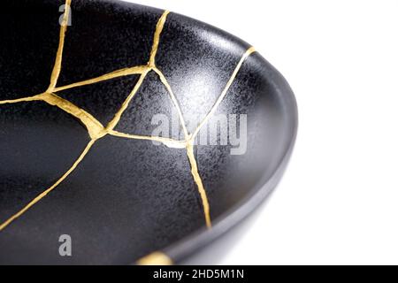 Kintsugi Gold Risse Restaurierung, japanische schwarze Schale mit der antiken Kintsukuroi Restaurierung Technik, die Schönheit der Unvollkommenheiten, fixiert, darstellen Stockfoto
