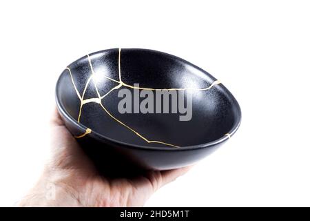 Kintsugi Gold Risse Restaurierung, japanische schwarze Schale mit der antiken Kintsukuroi Restaurierung Technik, die Schönheit der Unvollkommenheiten, fixiert, darstellen Stockfoto