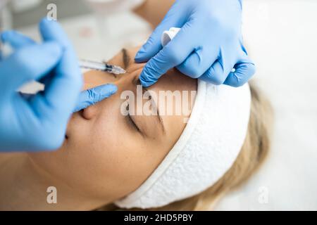 Kosmetikerin macht Botox-Injektionen im Bereich zwischen den Augenbrauen. Anti-Aging-Verfahren Stockfoto