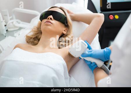 Hübsche Frau mit Achsellaser Haarentfernung Verfahren im Schönheitssalon. Hautpflege. Stockfoto