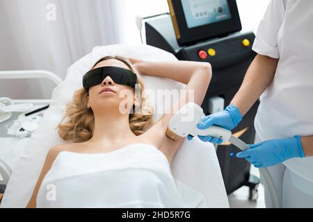 Schönes Mädchen auf einem Laser-Haarentfernung Verfahren Achselhöhlen in Kosmetologie Salon. Glatte und seidige Haut Konzept Stockfoto