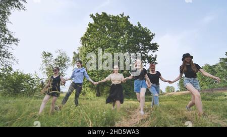 Schulmädchen-Freunde laufen außerhalb der Stadt entlang einer Waldstraße. Stockfoto