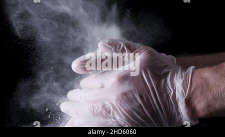 Koch klatscht mit Mehl in Zeitlupe auf schwarzem Hintergrund. Rahmen. Der Koch Klatscht Mit Mehl, Super Slow Motion, Die Hände Zusammen. Stockfoto