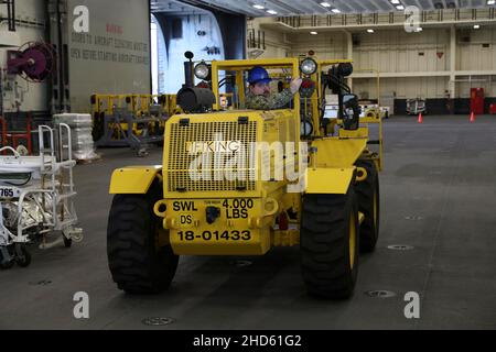 220103-N-VJ326-1111 (Jan 3, 2022) Logistik-Spezialist 3rd Klasse Daniel Glumm aus Bay City, Michigan, betreibt einen Gabelstapler in der Hangarbucht an Bord des amphibischen Angriffsschiffs USS Tripoli (LHA 7), Januar 3. Tripoli ist ein Amphibienschiff der amerikanischen Klasse, das in San Diego homeportiert wurde. (USA Navy Foto von Mass Communication Specialist 2nd Class Malcolm Kelley) Stockfoto