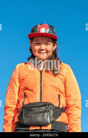 Mädchen in der leuchtend orangefarbenen Jacke, Ittoqqortoormiit, Scoresby Sund, Ostgrönland Stockfoto