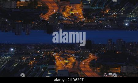 Die Skyline der Nacht und die Stadt mit vielen hellen Lichtern und Autos, die sich auf den Straßen bewegen, spiegeln den Horizont-Effekt wider. Atemberaubende Nachtlandschaft mit Gebäuden, Skysc Stockfoto