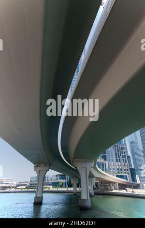 Unter einer gebogenen Betonstraßenbrücke über den Dubai Canal und das führende tp Business District Dubai Stockfoto