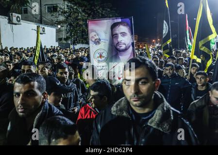 Gaza-Stadt, Palästina. 03rd Januar 2022. Demonstranten des Palästinensischen Islamischen Jihad marschieren mit Fahnen und Transparenten von Hisham Abu Hawasch, 40, der seit mehr als 140 Tagen in Hungerstreik ist, nachdem er von Israel verhaftet und in Verwaltungshaft genommen wurde. Kredit: SOPA Images Limited/Alamy Live Nachrichten Stockfoto