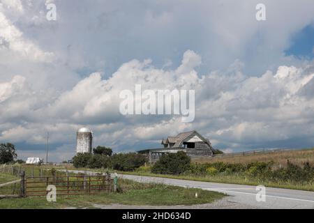 Eine Sommeransicht eines Silos und einer verlassenen Scheune auf einem New England grasbewachsenen Hügel mit Himmel und Cumuluswolken als Hintergrund Stockfoto