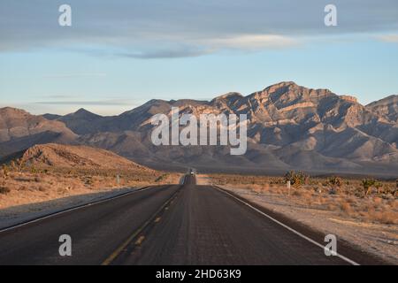Eine spektakuläre offene Straße und Blick auf die Berge bei Sonnenuntergang im Winter vom Highway 375 in Richtung Süden in Richtung Crystal Springs in Nevada, USA. Stockfoto