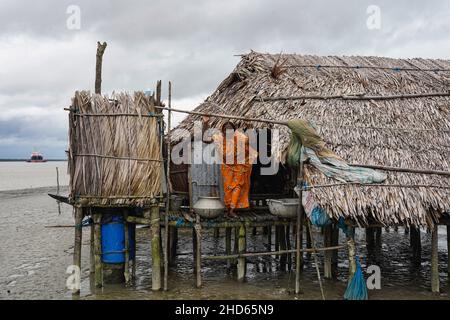 Mongla, Bangladesch. 12th September 2021. Eine Frau steht vor ihrem Haus, das aufgrund eines Wirbelsturms im Küstengebiet des Dorfes Jaymani mehrmals wiederaufgebaut wird.Bangladesch ist eines der Länder, das am stärksten von den Auswirkungen des Klimawandels betroffen ist. Die regelmäßigen und schweren Naturgefahren, die Bangladesch bereits unter tropischen Wirbelstürmen, Hochwasser, Flußerosion, Überschwemmungen, Erdrutschen und Dürren leidet, werden durch den Klimawandel immer intensiver und häufiger werden. (Foto von Sultan Mahmud Mukut/SOPA Image/Sipa USA) Quelle: SIPA USA/Alamy Live News Stockfoto