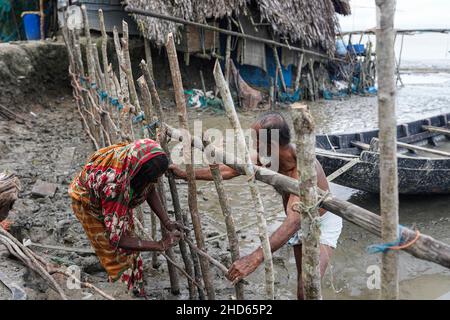 Mongla, Bangladesch. 12th September 2021. Ein alter Mann mit seiner Frau baut den Zaun wieder auf, um das von Flut durchbrach Embargo im Küstengebiet des Dorfes Jaymani zu schützen.Bangladesch ist eines der Länder, die am stärksten von den Auswirkungen des Klimawandels betroffen sind. Die regelmäßigen und schweren Naturgefahren, die Bangladesch bereits unter tropischen Wirbelstürmen, Hochwasser, Flußerosion, Überschwemmungen, Erdrutschen und Dürren leidet, werden durch den Klimawandel immer intensiver und häufiger werden. (Foto von Sultan Mahmud Mukut/SOPA Image/Sipa USA) Quelle: SIPA USA/Alamy Live News Stockfoto