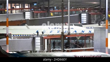 Hamburg, Deutschland. 04th Januar 2022. Rückkehrpassagiere des Kreuzfahrtschiffs 'Aida Nova' laufen in der Nacht durch eine Gangway am Hamburger Flughafen, nachdem sie von einem von zwei gecharterten Flugzeugen nach Deutschland zurückgebracht wurden. Die Reederei Aida Cruises hatte beschlossen, die Reise der 'Aida Nova' in Lissabon nach den Fällen einer Infektion mit Covid-19 unter der Besatzung abzubrechen. Quelle: Jonas Walzberg/dpa/Alamy Live News Stockfoto