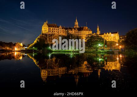 Schloss Hohenzollern in Sigmaringen, Deutschland, spiegelt sich in der Nacht im Wasser der Donau wider Stockfoto