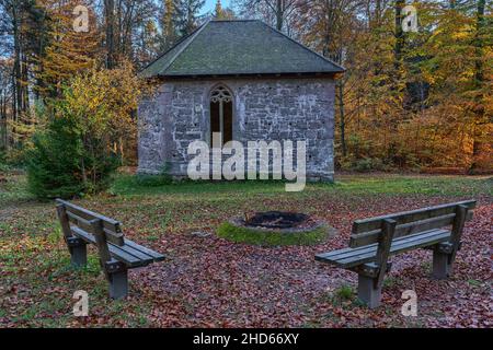 Kleine Kirche im Wald mit Kamin und zwei Bänken Stockfoto