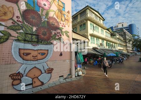 Szene entlang der Ong Ang Walking Street entlang des Klong (Kanal) Ong Ang in Phahurat/Chinatown in Bangkok, Thailand; links: Ein Wandbild des thailändischen Künstlers Alex Face Stockfoto