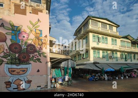 Szene entlang der Ong Ang Walking Street entlang des Klong (Kanal) Ong Ang in Phahurat/Chinatown in Bangkok, Thailand; links: Ein Wandbild des thailändischen Künstlers Alex Face Stockfoto