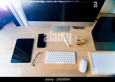 Nahaufnahme des Arbeitsplattes im Büro mit Holztisch und Laptop-Verlegung, Arbeitsplatz. Komfortabler Arbeitsplatz mit Laptop Espresso Smartphone Notizblock Papier Stift Brillen Maus darauf legen. Hochwertige Fotos Stockfoto