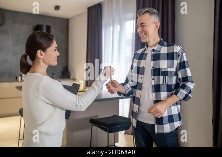 Frau mit Ordner, der dem glücklichen Mann Schlüssel gibt Stockfoto