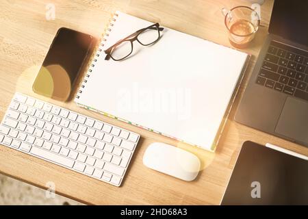 Nahaufnahme des Arbeitsplattes im Büro mit Holztisch und Laptop-Verlegung, Arbeitsplatz. Komfortabler Arbeitsplatz mit Laptop Espresso Smartphone Notizblock Papier Stift Brillen Maus darauf legen. Hochwertige Fotos Stockfoto