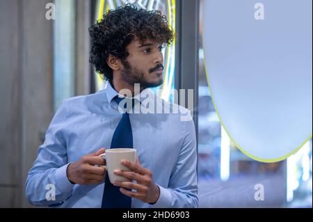 Junger eleganter Geschäftsmann mit einer Tasse in den Händen Stockfoto
