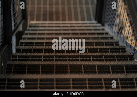 Nahaufnahme einer Stahltreppe, die bei schwachem Licht nach unten geht. Selektive Fokuspunkte. Stockfoto