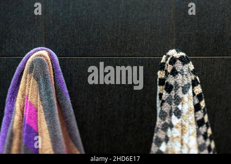 Shallow dof-Aufnahme von zwei bunten Badetüchern, die an der Wand des Badezimmers hängen, Tilt-Shift aus nächster Nähe Stockfoto