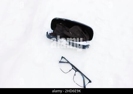 Brille und Koffer auf dem Schnee abgelegt, Nahaufnahme im Freien Stockfoto