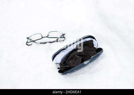 Brille und Koffer auf dem Schnee abgelegt, Nahaufnahme im Freien Stockfoto