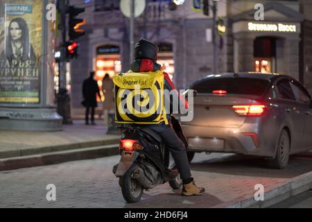 Krasnodar, Russland - Januar 03 2022: Yandex Food Delivery Boy auf Roller mit isothermen Lebensmittel-Fall Stockfoto