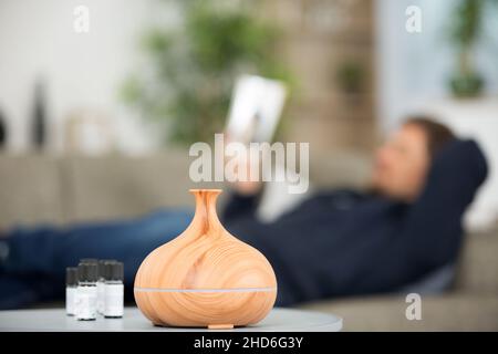 Mann entspannt ein Buch zu lesen, wie Diffusor emittiert ätherische Öle Stockfoto