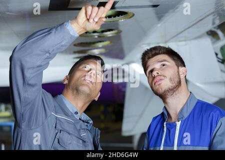 Mechanik, die das Fahrwerk eines Flugzeugs inspiziert Stockfoto