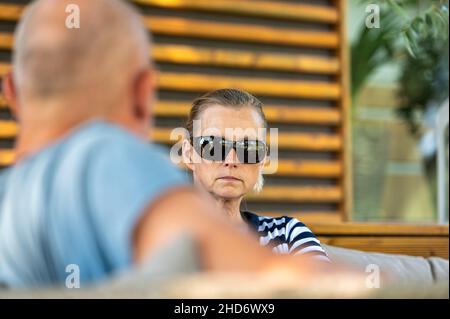 Ehepaar mittleren Alters, die sich im Garten entspannen und reden, Nahaufnahme Porträt einer Frau Stockfoto