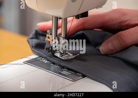 Nähprozess. Nahaufnahme der Reparatur von Kleidung, Nähen auf einer Nähmaschine. Reparaturkonzept für Kleidung. Hobby oder Geld verdienen durch Nähen von Kleidung Stockfoto