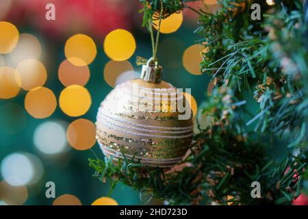 Flacher Fokus eines goldenen Ornaments auf Weihnachtsbaum mit verschwommenem Bokeh-Licht, Weihnachtszeit Stockfoto