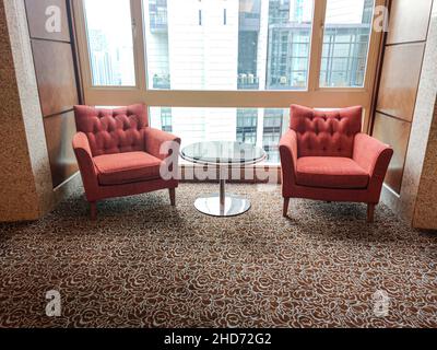 Zwei Einsitzer-Sofa mit Beistelltisch aus Glas vor einem Glasfenster. Selektive Fokuspunkte. Stockfoto