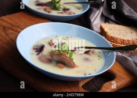 Cremige Suppe mit Steinpilzen und Kräutern auf rustikalem Holztisch Stockfoto