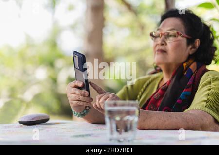 Ältere Frau, die im Garten Smartphone im Freien benutzt. Stockfoto