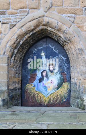 Wandbild von Maria Joseph und dem Jesuskind an den Kirchentüren mit Mauerwerk-Torbogen in der St. Thomas the Martyr Church, Upholland, Lancashire, Großbritannien, Stockfoto